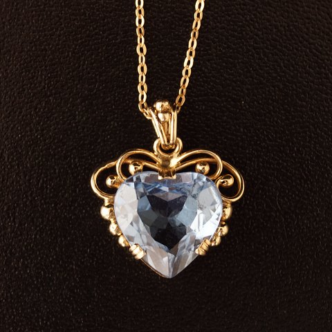 A necklace of 14k gold, set with a blue topaz pendant, shaped as a heart with 8k gold chain