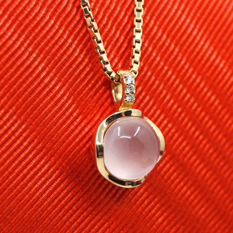 A pendant in 14k gold set with a rose quartz and diamonds